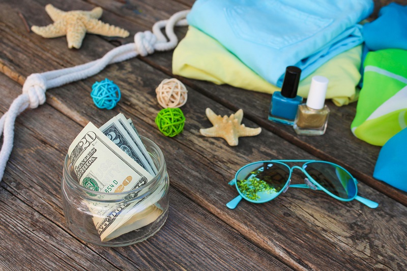 Money on deck with towels, seashells and sunglasses